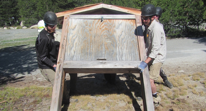 Two students raise a trail sign during a service project with outward bound. 